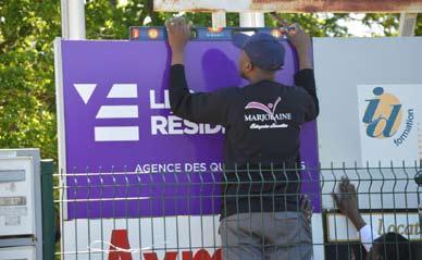 Livraison et pose d'un panneau Un agent de Marjolaine Entreprise en pleine pose d'une signalétique extérieure